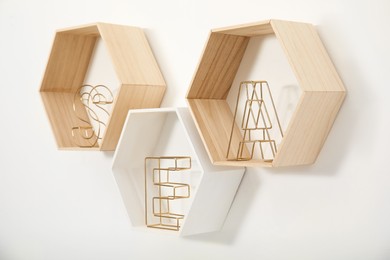 Photo of Honeycomb shaped shelves with decorative elements on white wall