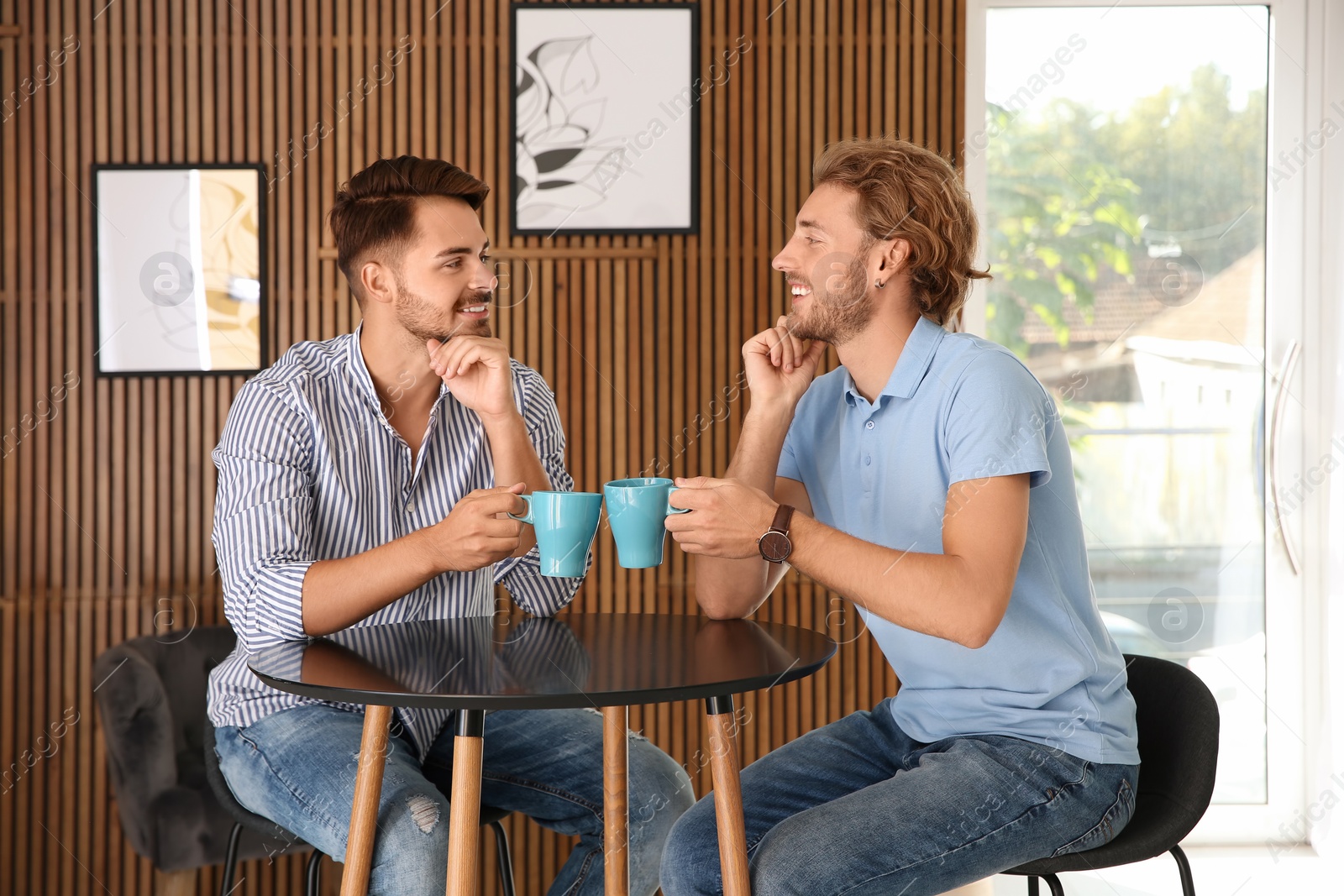 Photo of Happy gay couple with coffee at table indoors