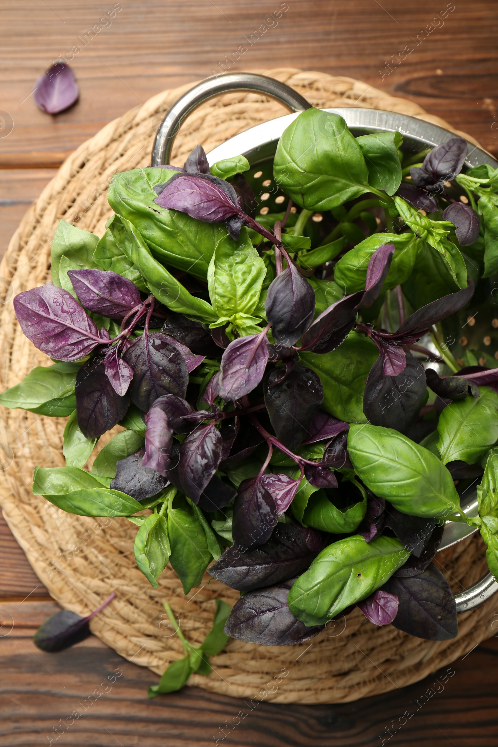 Photo of Metal colander with different fresh basil leaves on wooden table, top view