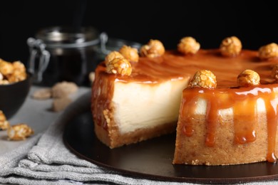 Photo of Sliced delicious cheesecake with caramel and popcorn on table, closeup