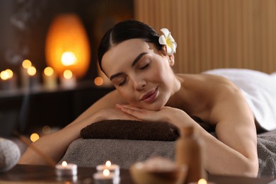 Spa therapy. Beautiful young woman lying on massage table in salon