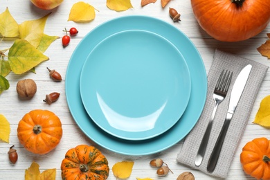 Flat lay composition with tableware, pumpkins and autumn leaves on white wooden background. Thanksgiving Day