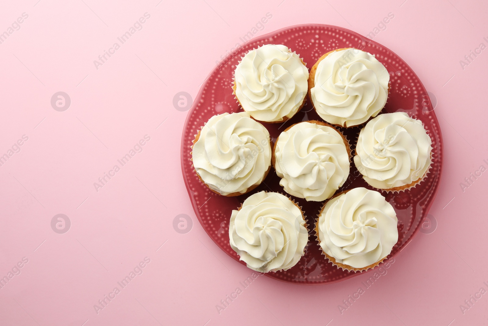 Photo of Tasty vanilla cupcakes with cream on pink background, top view. Space for text