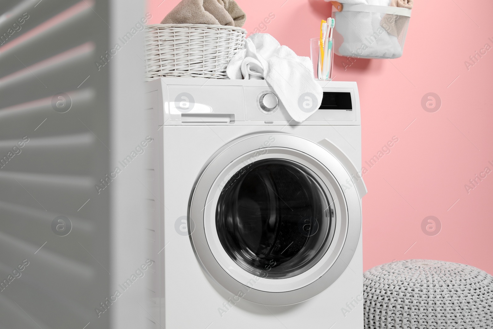 Photo of Modern washing machine near wall in laundry room