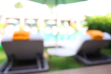 Photo of Sunbeds near swimming pool at luxury resort, blurred view