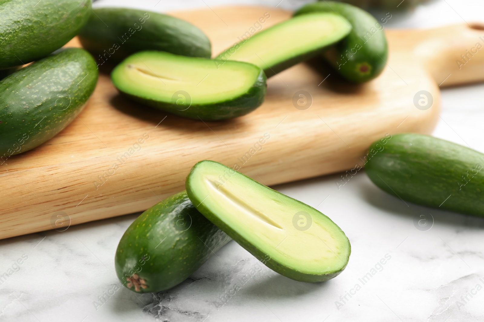 Photo of Fresh seedless avocados on marble table, closeup