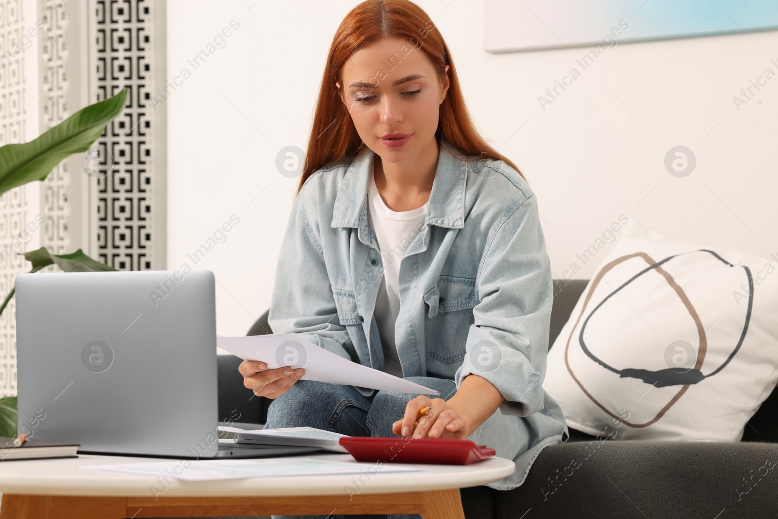 Photo of Woman calculating taxes at table in living room