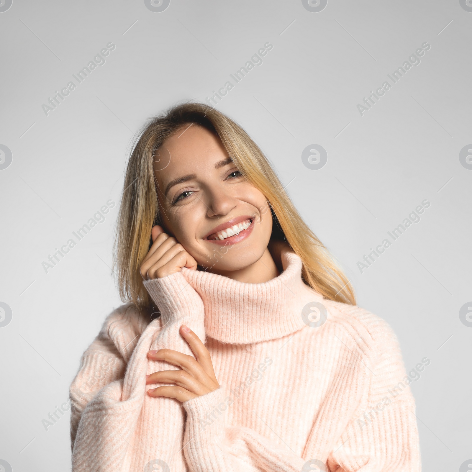 Photo of Beautiful young woman wearing knitted sweater on light grey background