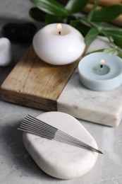 Stone with acupuncture needles on light grey marble table