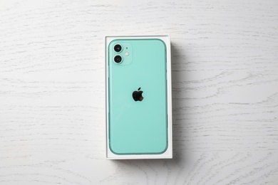 Photo of MYKOLAIV, UKRAINE - JULY 10, 2020: New modern Iphone 11 Green in original box on white wooden table, top view