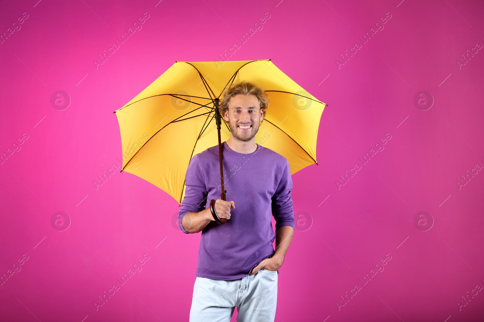 Photo of Man with yellow umbrella on color background