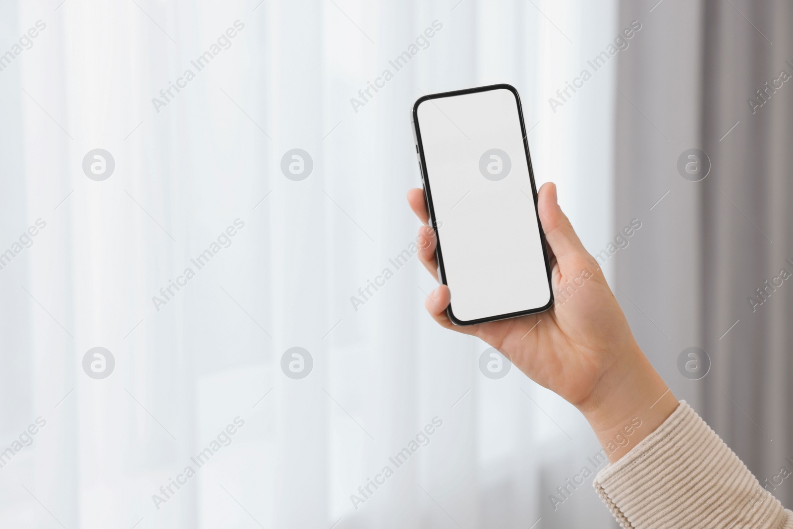 Photo of Woman holding smartphone in hand at home, closeup. Space for text