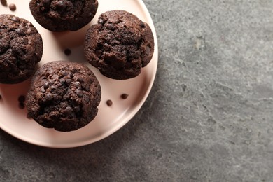 Photo of Delicious chocolate muffins on grey textured table, top view. Space for text