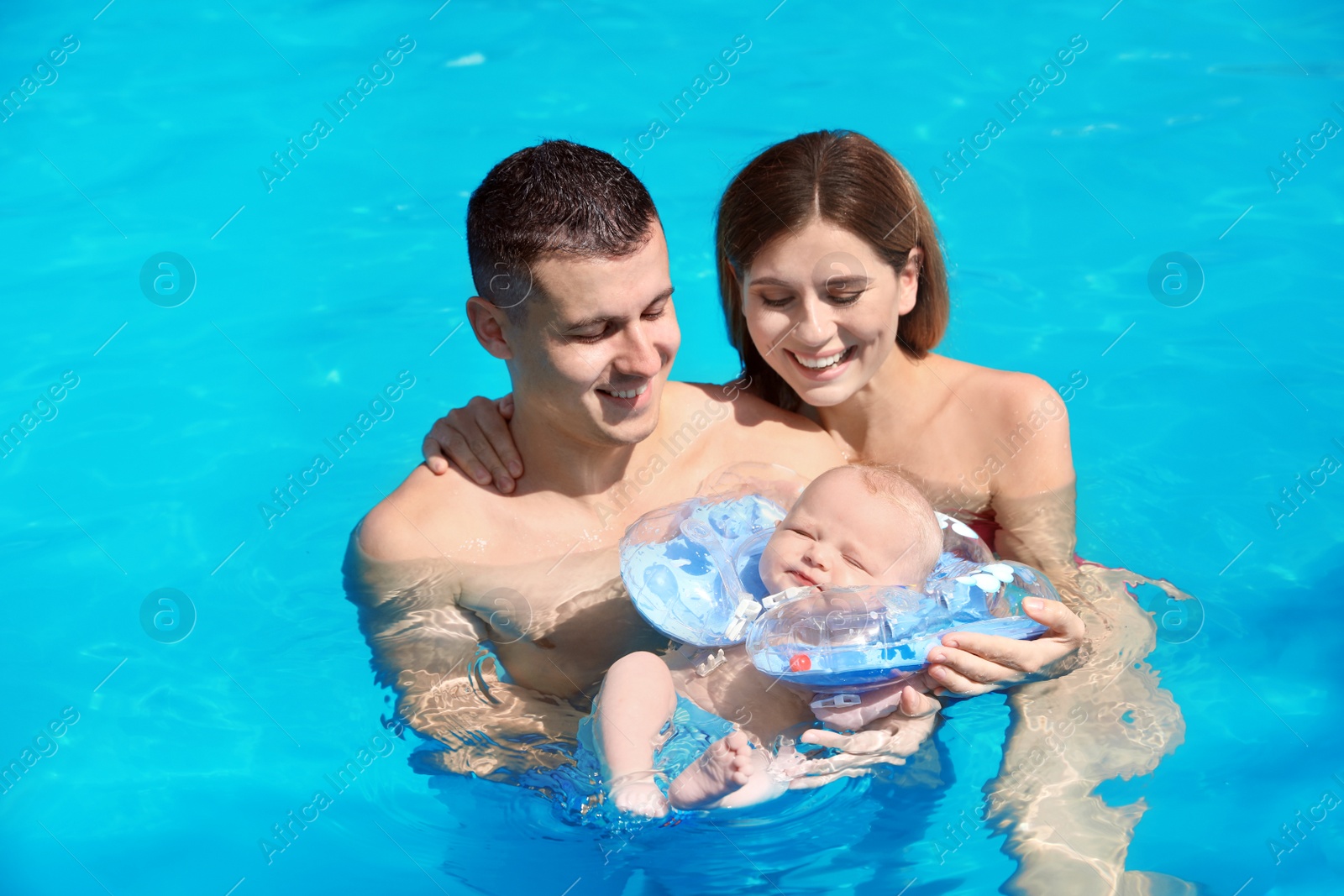 Photo of Happy parents with little baby in swimming pool on sunny day, outdoors
