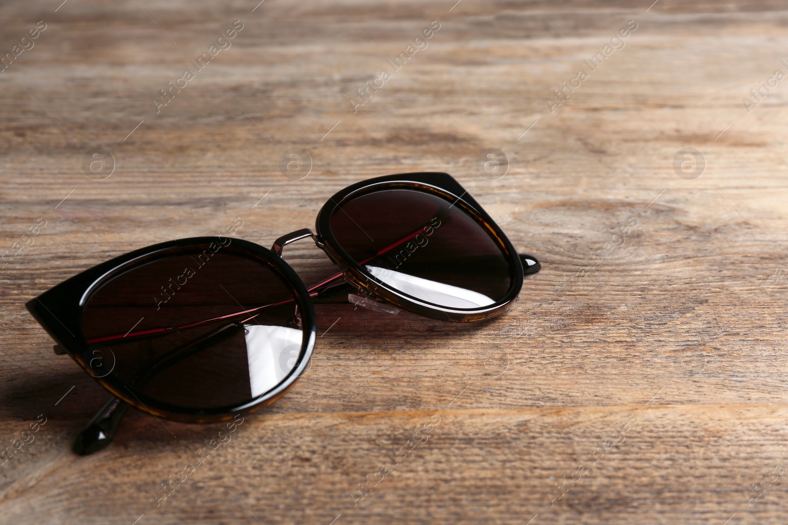 Photo of Stylish sunglasses on wooden background. Fashionable accessory