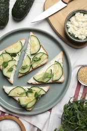 Photo of Tasty cucumber sandwiches with sesame seeds and pea microgreens on white table, flat lay