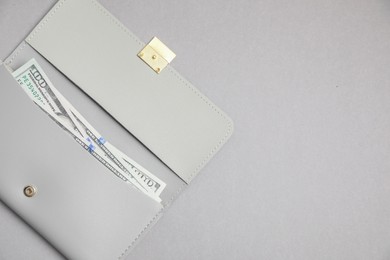 Photo of Stylish leather purse with dollar banknotes on light grey background, top view. Space for text