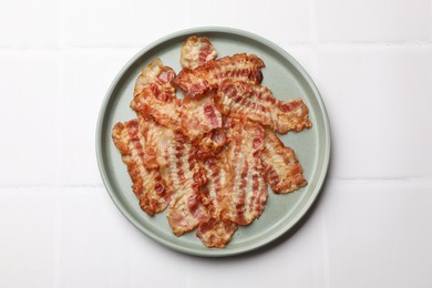 Delicious fried bacon slices on white wooden table, top view