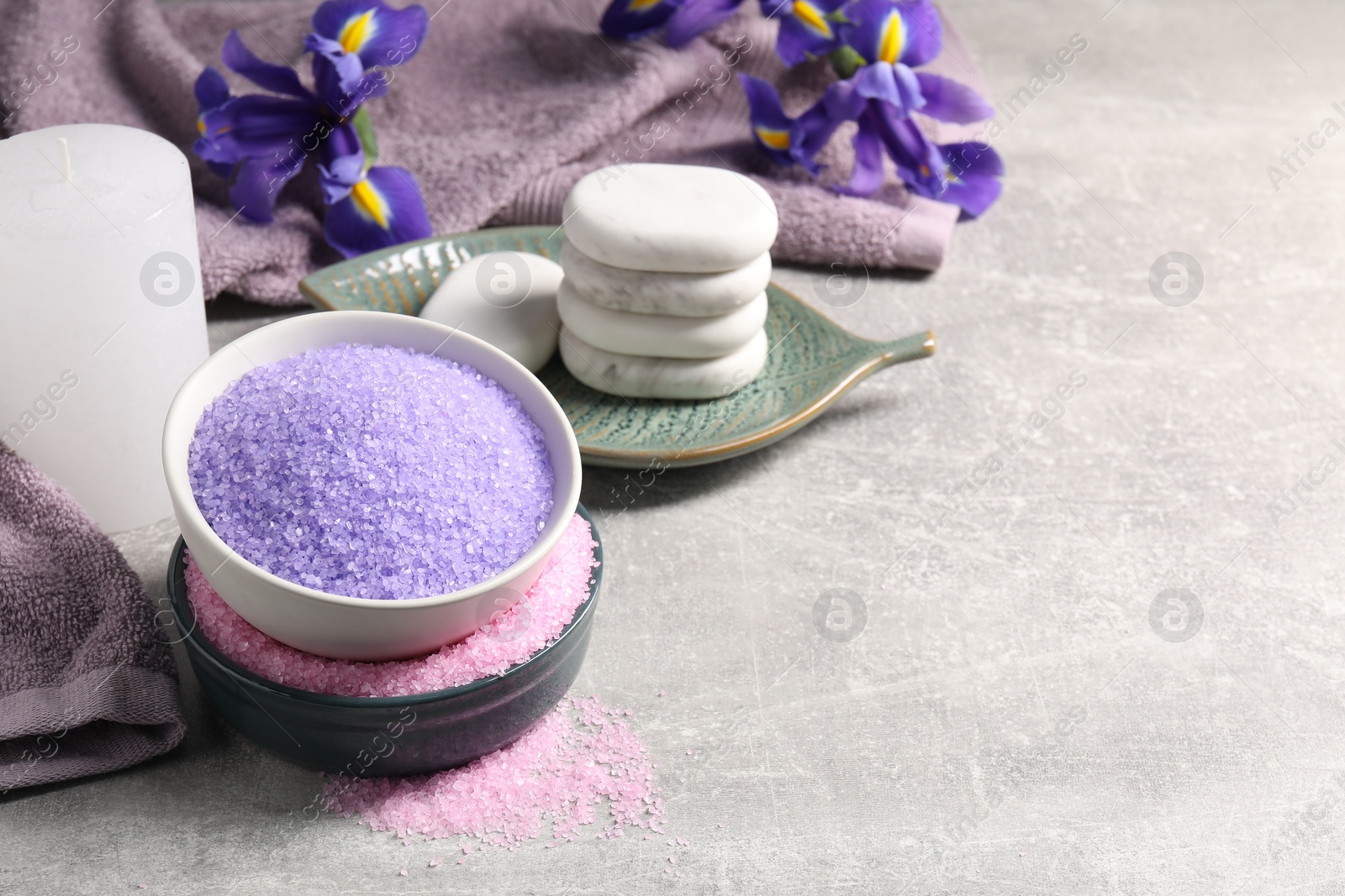 Photo of Different types of sea salt and spa stones on grey table, space for text