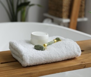 Photo of Wooden tray with spa products on bath tub in bathroom