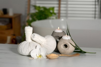 Photo of Composition with spa products, plumeria flower and burning candles on white table indoors