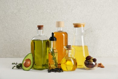 Vegetable fats. Different cooking oils in glass bottles and ingredients on white table