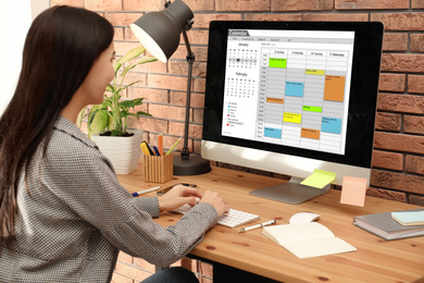 Photo of Young woman using calendar app on computer in office