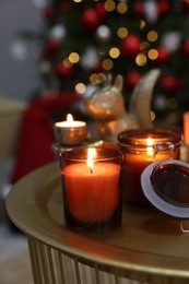 Photo of Burning candles on table in room decorated for Christmas