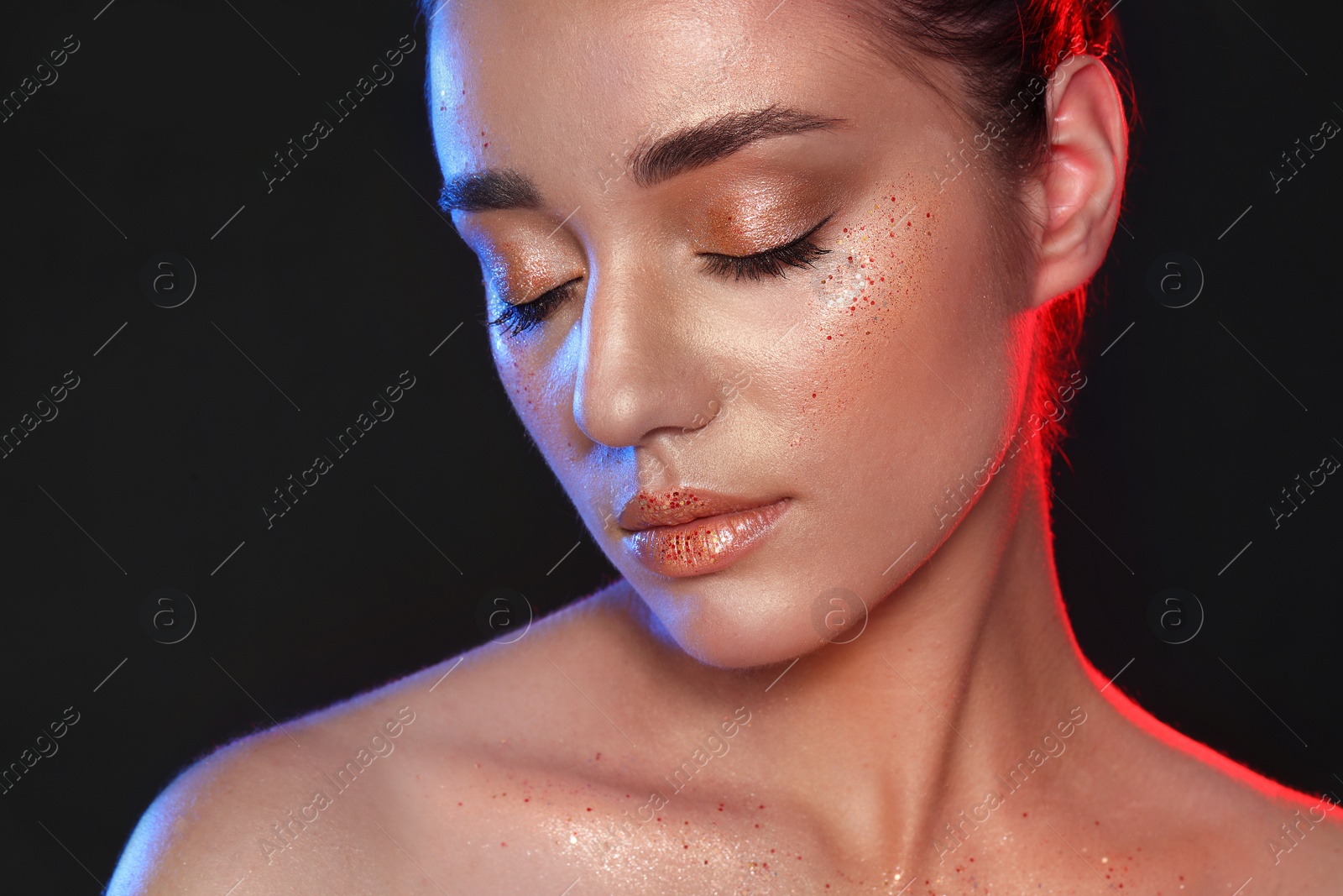 Photo of Beautiful young woman with glitter makeup on black background