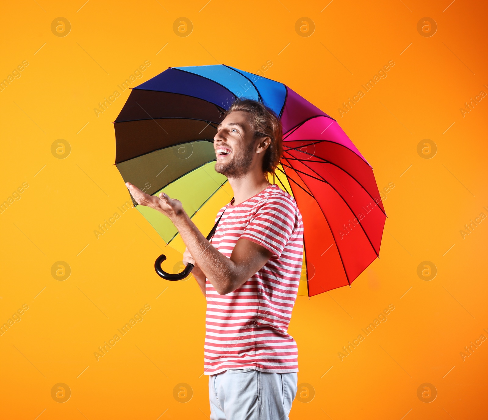 Photo of Man with rainbow umbrella on color background