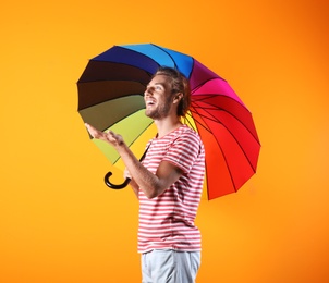 Photo of Man with rainbow umbrella on color background