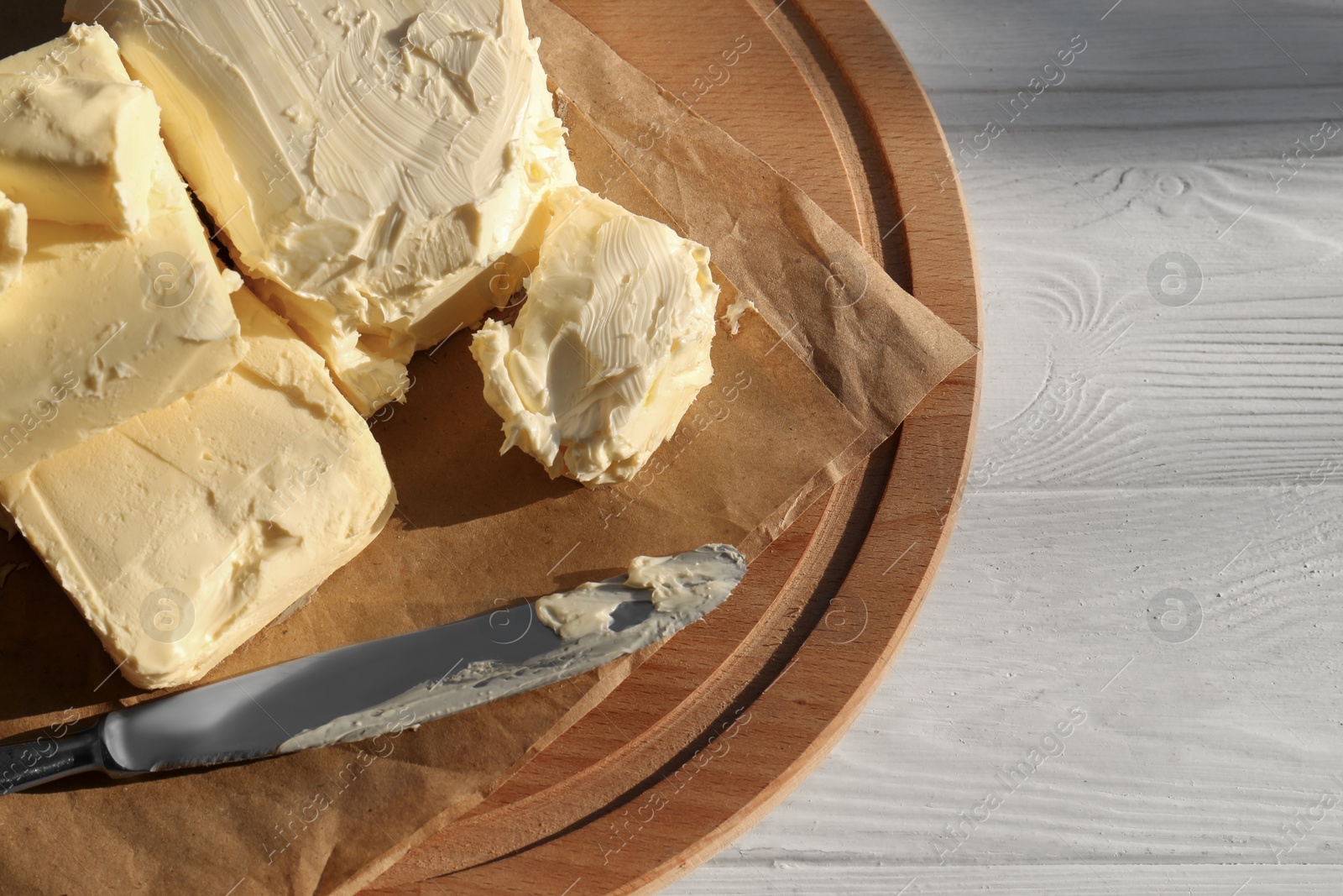 Photo of Tray with tasty homemade butter and knife on white wooden table, top view