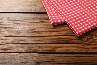 Photo of Red checkered tablecloth on wooden table, space for text