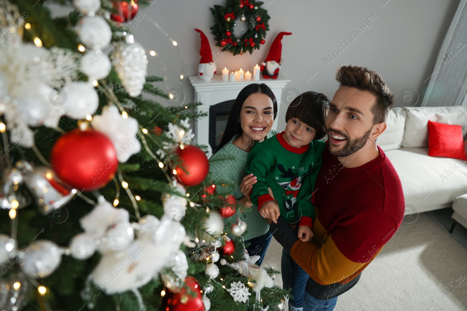 Photo of Happy family decorating Christmas tree together at home, above view