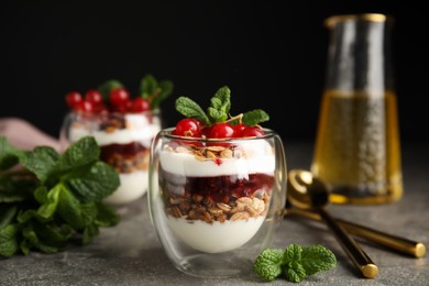 Photo of Delicious yogurt parfait with fresh red currants and mint on grey table