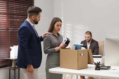 Colleague comforting dismissed young woman in office