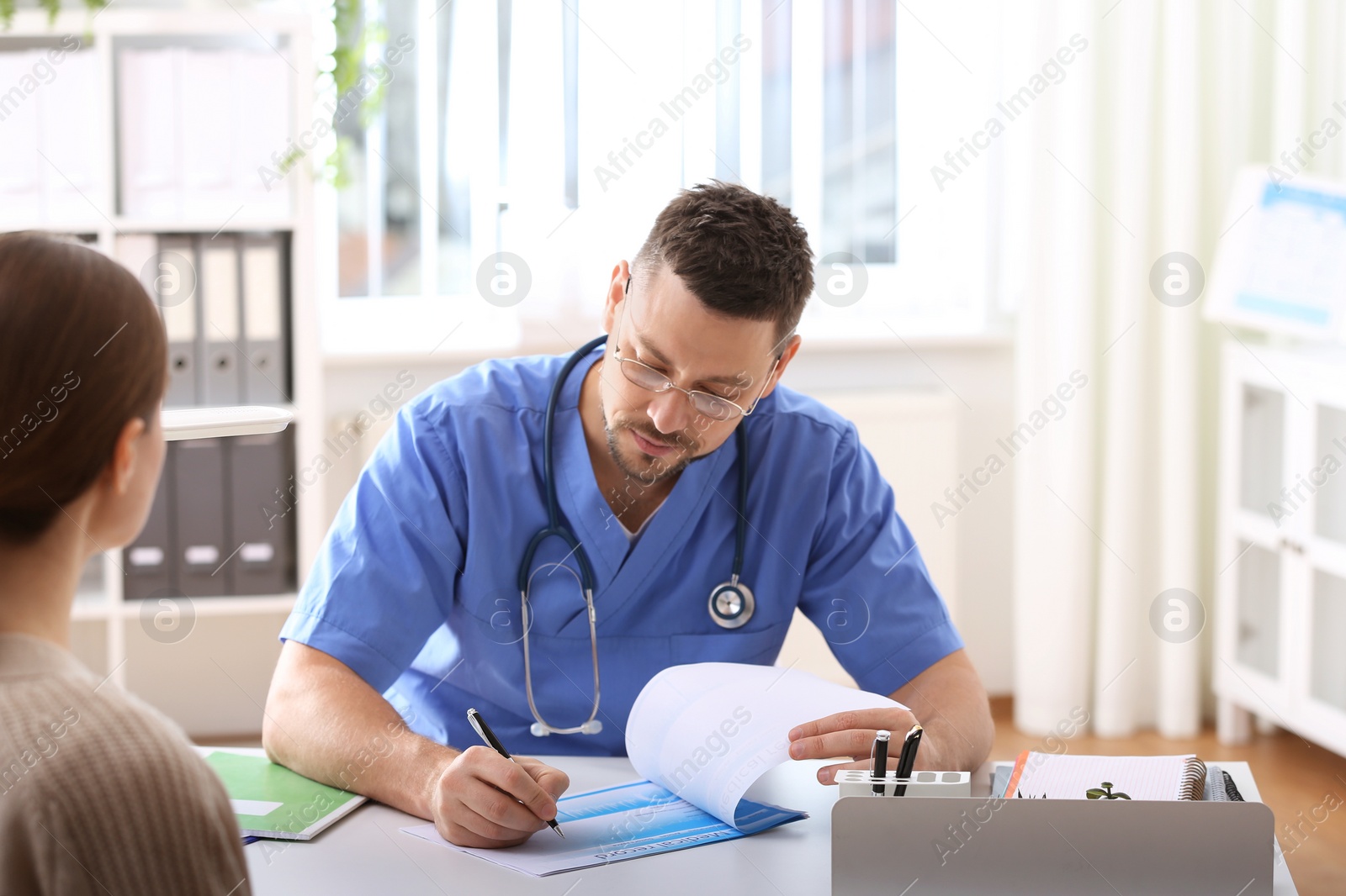 Photo of Doctor consulting patient at desk in clinic
