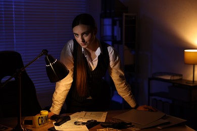 Photo of Professional detective working at table in office at night