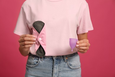 Young woman with reusable pad and menstrual cup on bright pink background, closeup