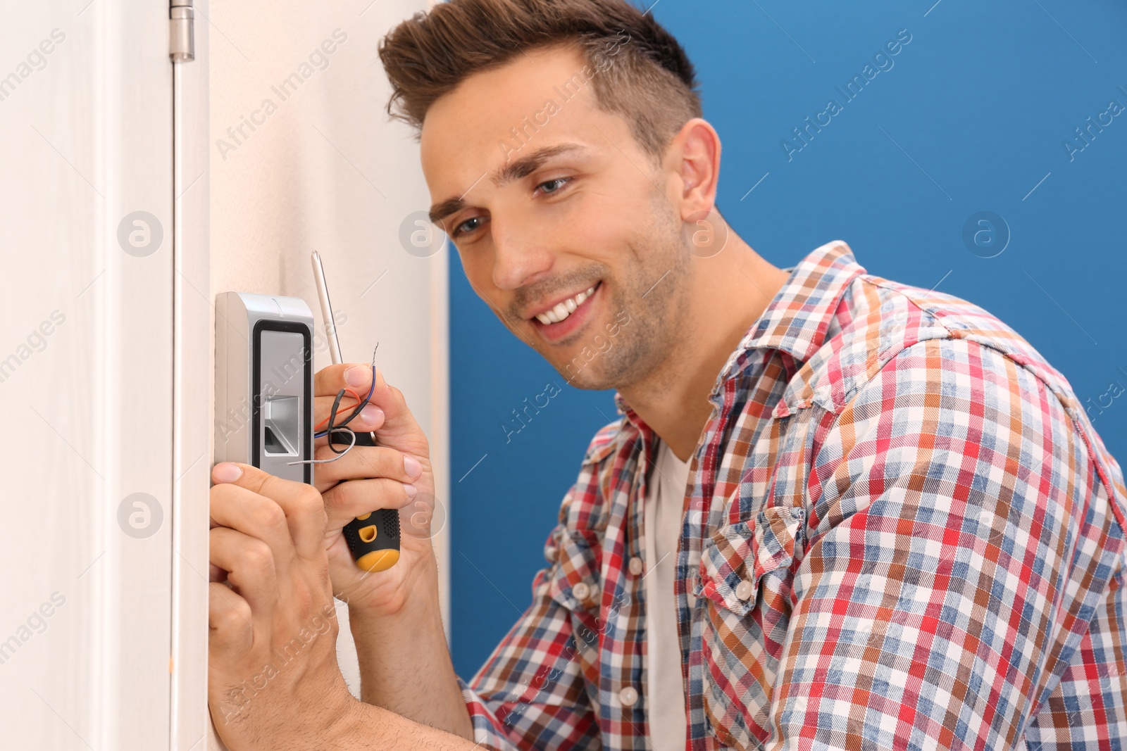 Photo of Young man installing fingerprint security alarm system indoors