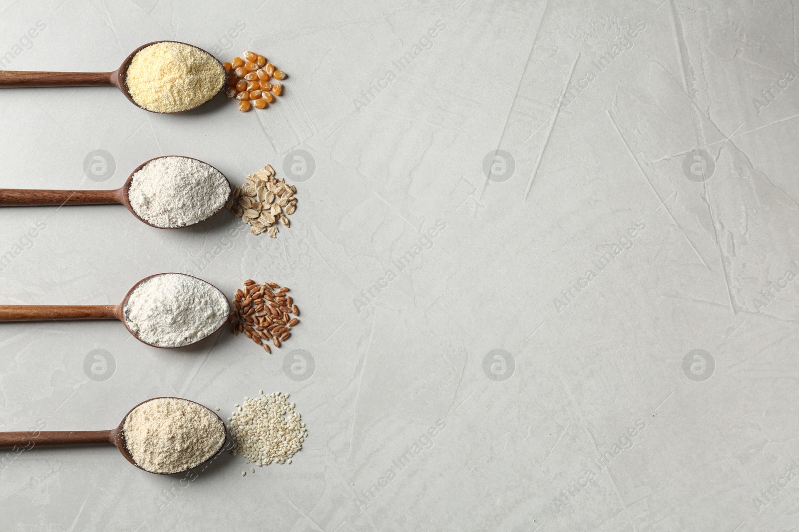 Photo of Spoons with different types of flour and ingredients on table, flat lay. Space for text