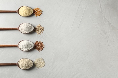 Photo of Spoons with different types of flour and ingredients on table, flat lay. Space for text