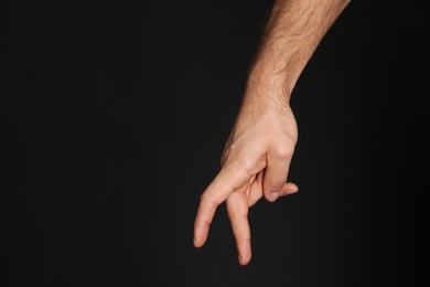 Man imitating walk with hand on black background, closeup. Finger gesture