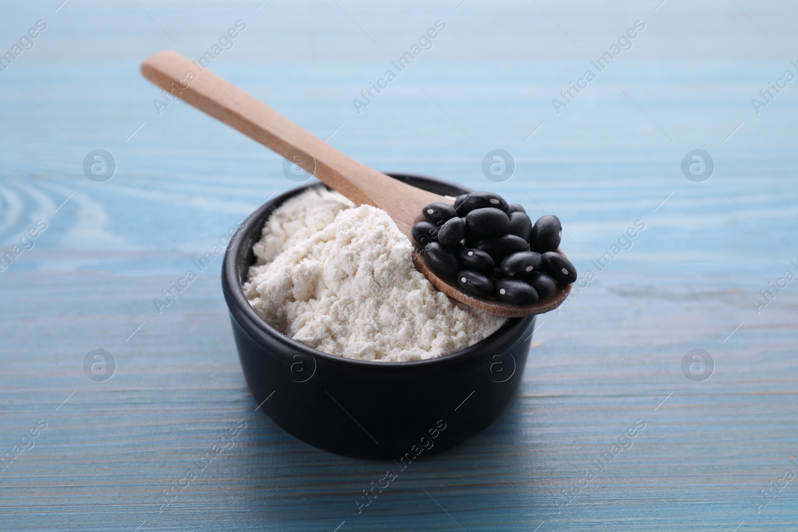 Kidney bean flour and black seeds on light blue wooden table Photo of Kidney bean flour and black seeds on light blue wooden table