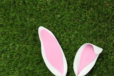 Photo of Funny Easter bunny ears on green grass, top view with space for text