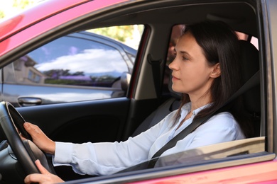 Woman with fastened safety belt on driver's seat in car