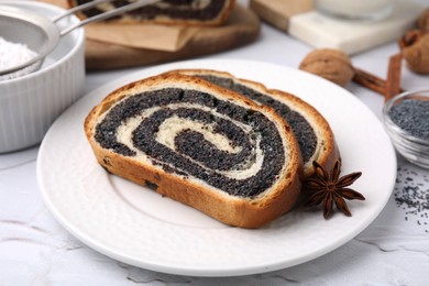 Photo of Slices of poppy seed roll and anise star on white textured table, closeup. Tasty cake