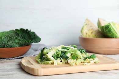 Photo of Cutting board with chopped savoy cabbage on table