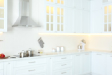 Photo of Blurred view of modern kitchen interior with white furniture