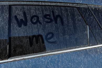 Inscription Wash me on dirty car window, closeup